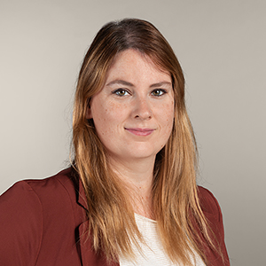 Porträtbild von Noreen Koch. Eine junge Frau mit braunen Haaren, grünen Augen und einem freundlichen Lachen.